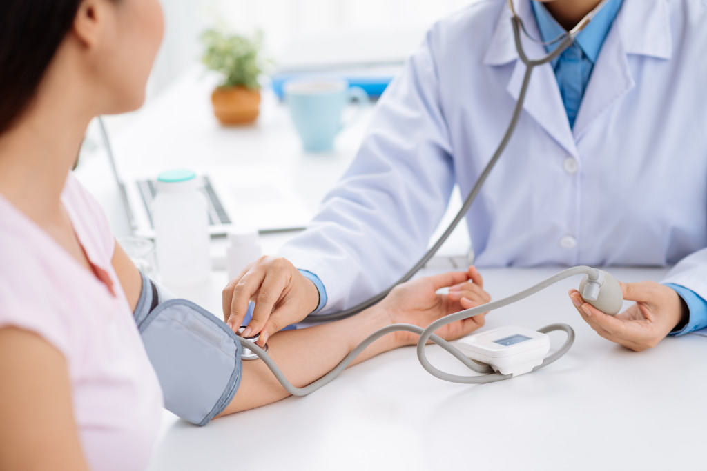 Bác sĩ đang tiến hành đo huyết áp và kiểm tra sức khỏe tổng quát cho du học sinh