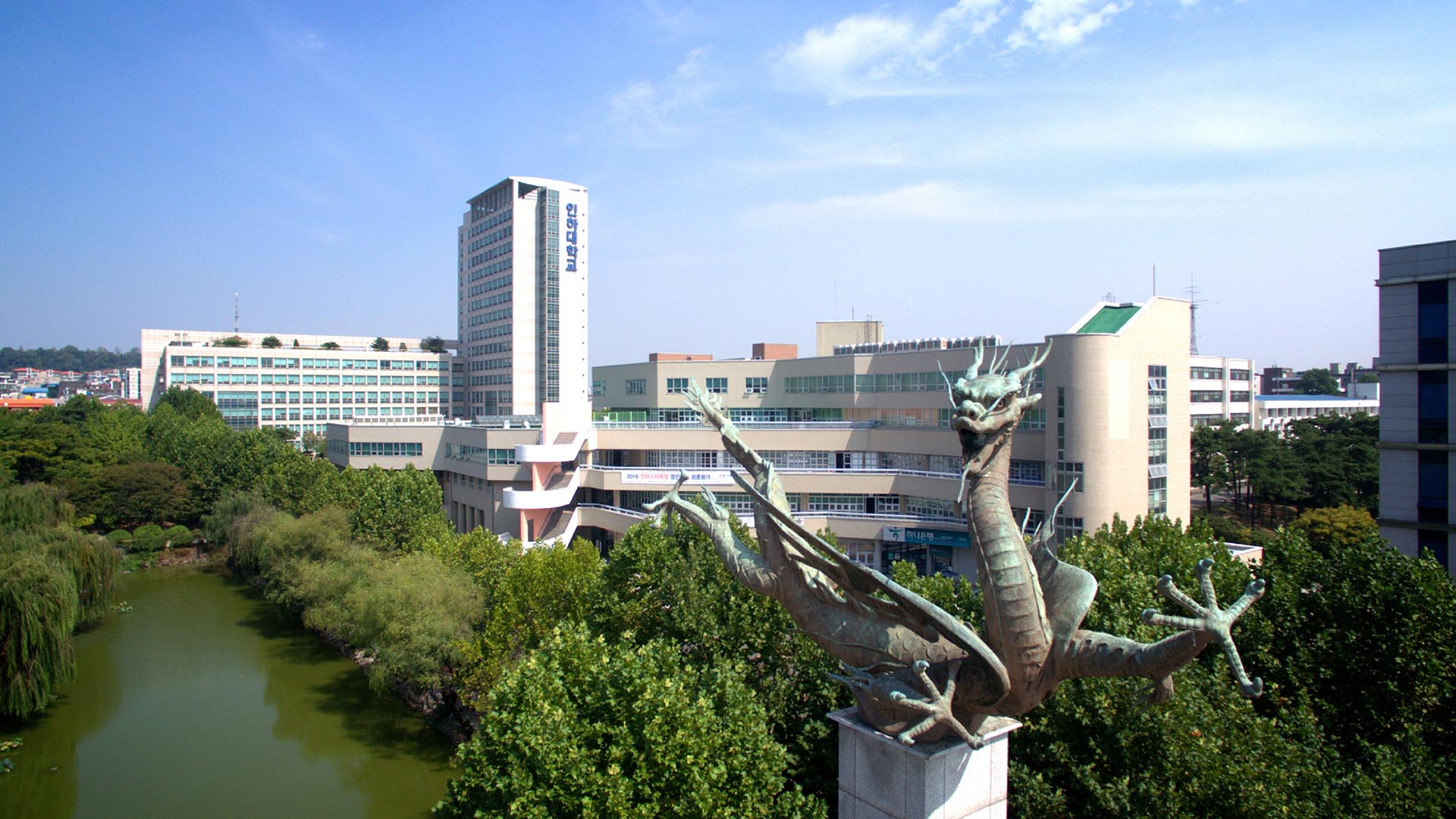 Toàn cảnh khuôn viên trường Đại học Inha (인하대학교) với hồ nước và tượng đài.