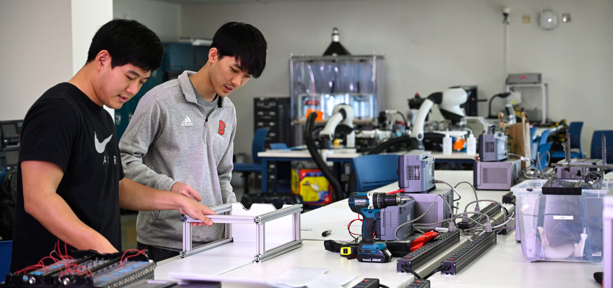 Hai sinh viên đang thực hành lắp ráp thiết bị phần cứng tại phòng lab của nhóm ngành Kỹ thuật máy tính và CNTT.